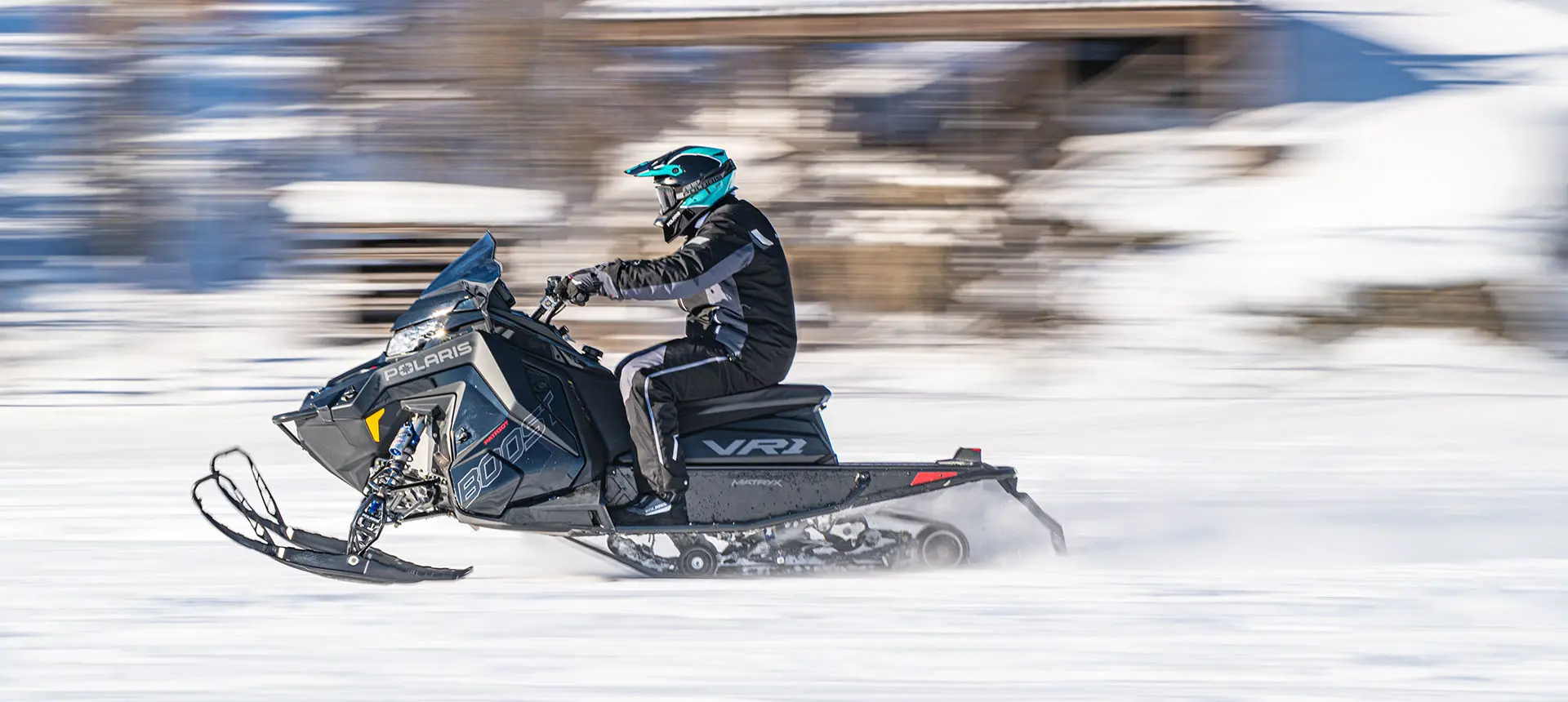 side view of an indy vr1 snowmobile cruising down a trail