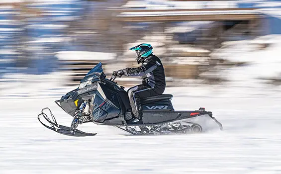 side view of an indy vr1 snowmobile cruising down a trail