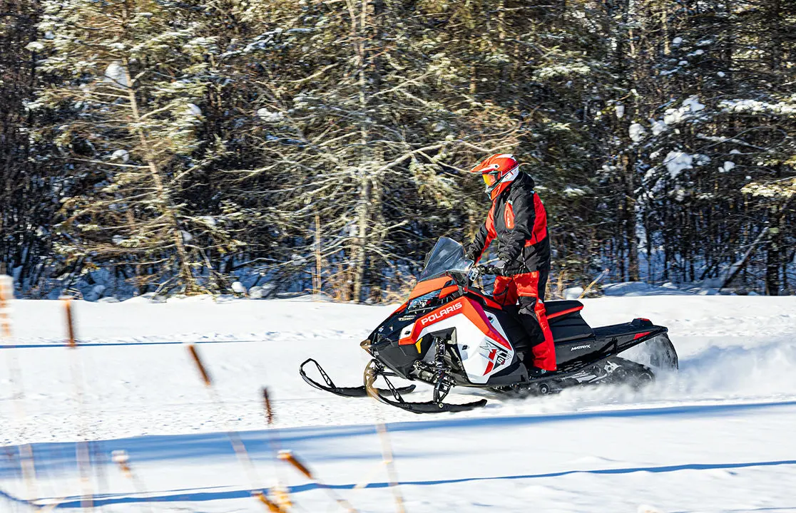 rider standing while driving a polaris indy xc snowmobile