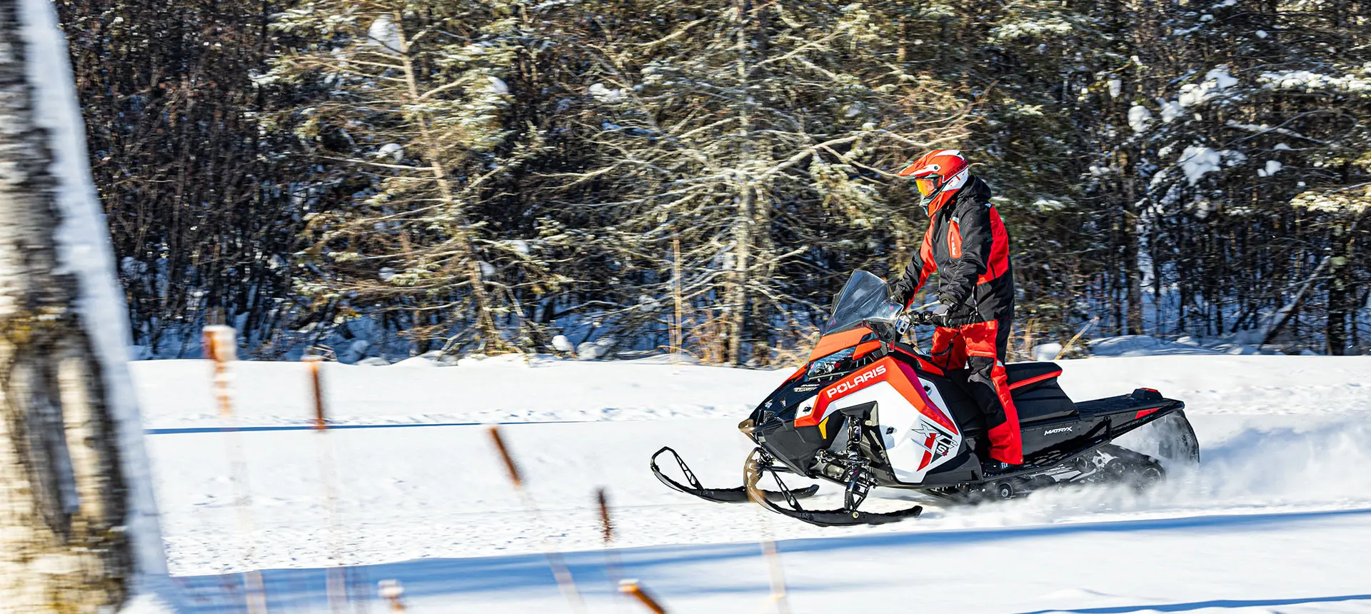 rider standing while driving a polaris indy xc snowmobile