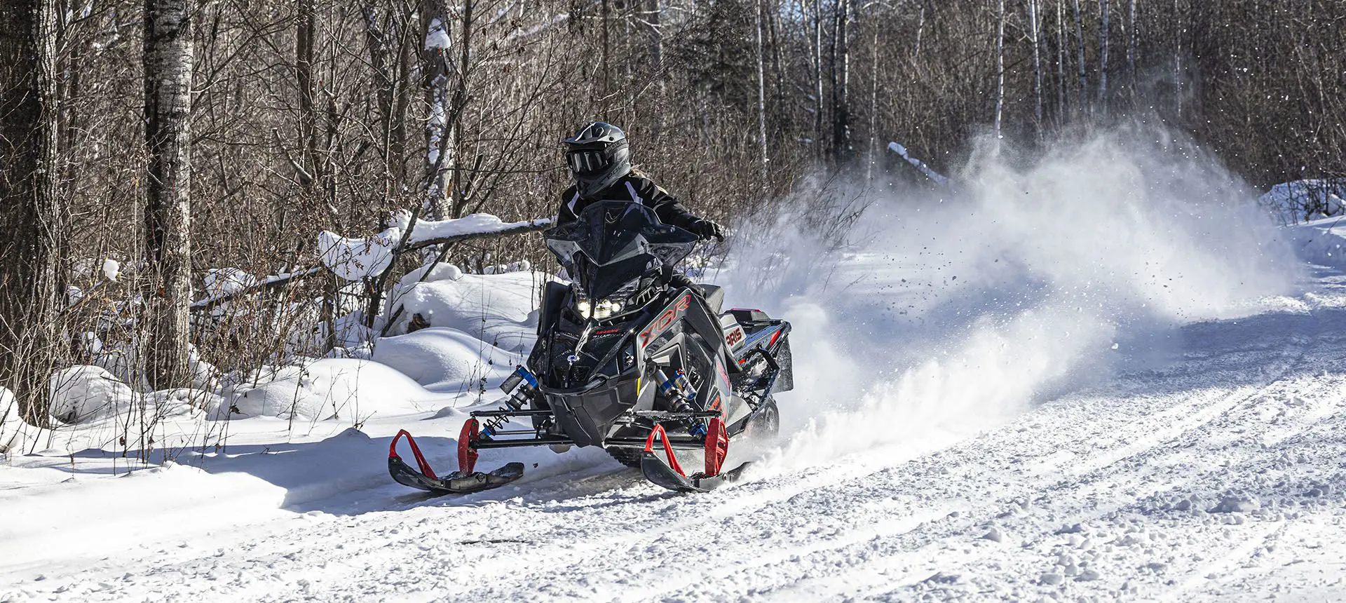 rider cruising down a trail on a polaris indy xcr snowmobile