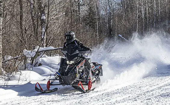 rider cruising down a trail on a polaris indy xcr snowmobile