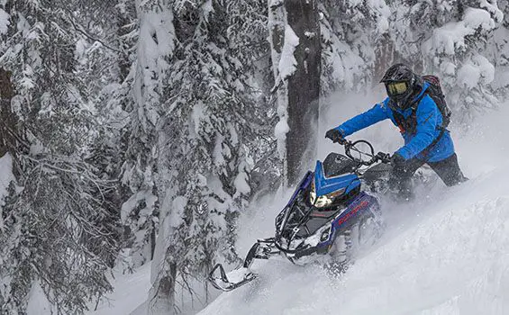 rider cutting through deep snow on his polaris pro rmk slash snowmobile