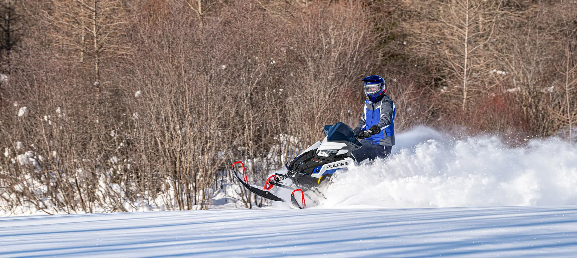rider on a polaris switchback xc snowmobile throwing snow