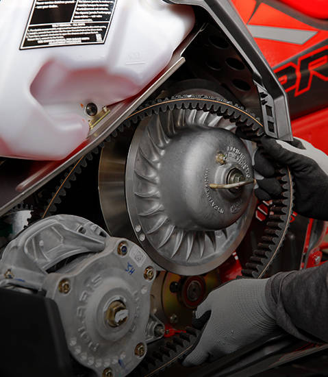 Close-up detail of a service technician replacing the belt on a Polaris Snowmobile.