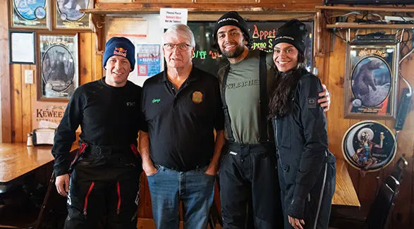 Levi LaVallee and friends, including Michelle Young and Jack Leius, wearing Polaris apparel, posing inside a restaurant decorated with vintage advertising signs.