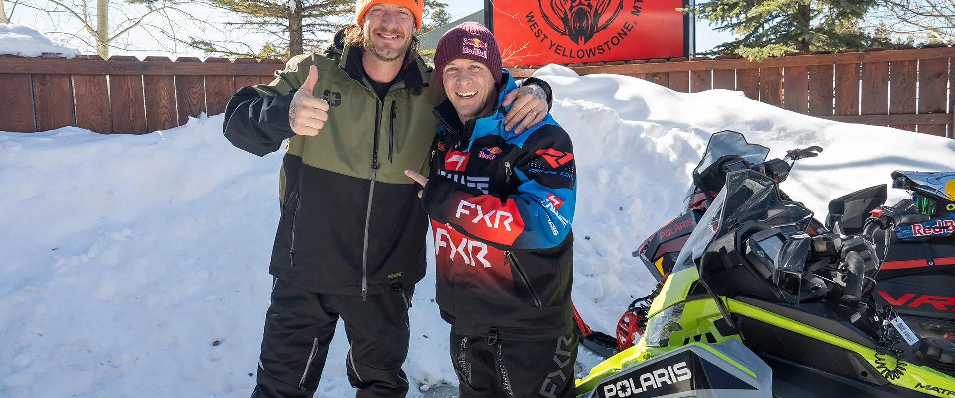 Levi LaVallee and Tyler Hubbard in West Yellowstone, Montana, wearing branded outerwear and standing next to Polaris snowmobiles.