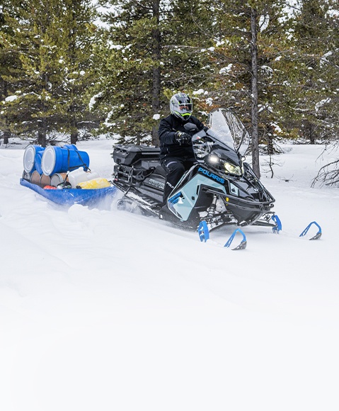 A rider pulling a sled with gear with a 2026 Polaris TITAN widetrack snowmobile.