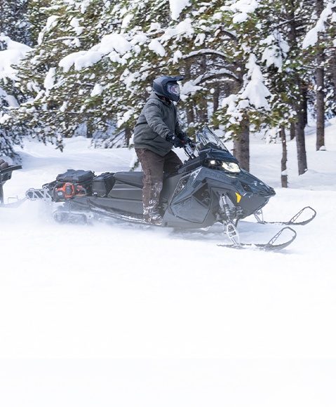 Rider cruising a trail on a 2026 Polaris Voyageur sport-utility snowmobile.