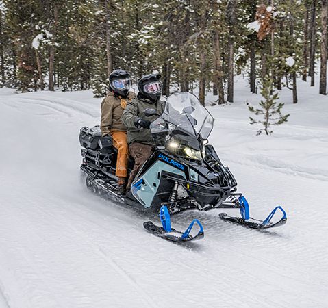 2 riders on the 2-up 2026 Polaris TITAN Adventure Ultimate 155 widetrack snowmobile trail riding with the fuel efficient ProStar S4 4-stroke engine. 