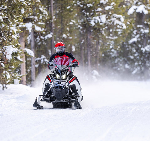 Rider cruising a trail on a 2026 Polaris 650 TITAN SP 155 widetrack snowmobile. 