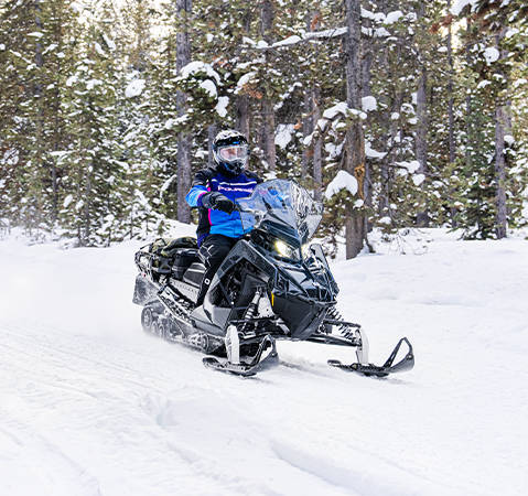 A rider on a 2026 Polaris Voyageur SP 155 sport-utility snowmobile showcasing the BackTrak15 articulated rear suspension.