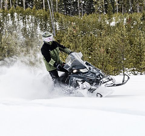 A rider on a 2026 Polaris Voyageur XC 155 sport-utility snowmobile leaning through a quick turn and showcasing the quick accelerating power of the 650 Patriot 2-stroke engine.
