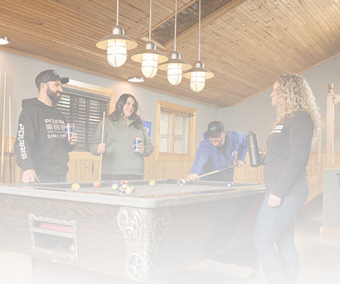 Two couples playing billiard and using Polaris Snowmobiles clothing and gear.
