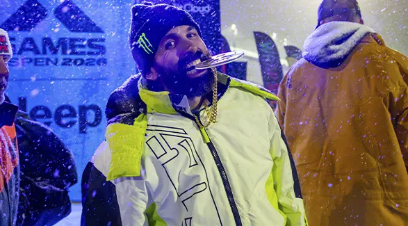 Brett Turcotte holding a medal between their teeth during a snowy X Games awards ceremony.