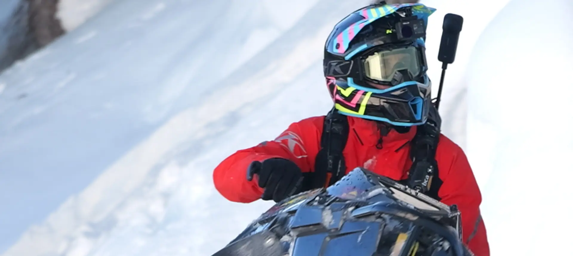 Chris Burandt in red winter gear equipped with a helmet camera and avalanche safety pack.