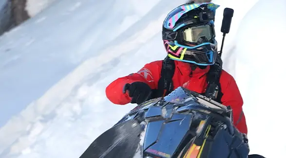 Chris Burandt in red winter gear equipped with a helmet camera and avalanche safety pack.