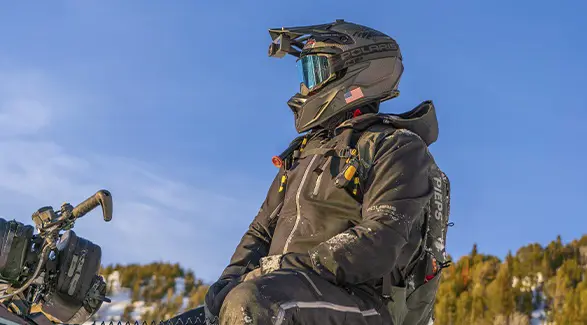 Kyle Pulsifer wearing a helmet camera, goggles and avalanche safety gear beneath a clear blue sky.