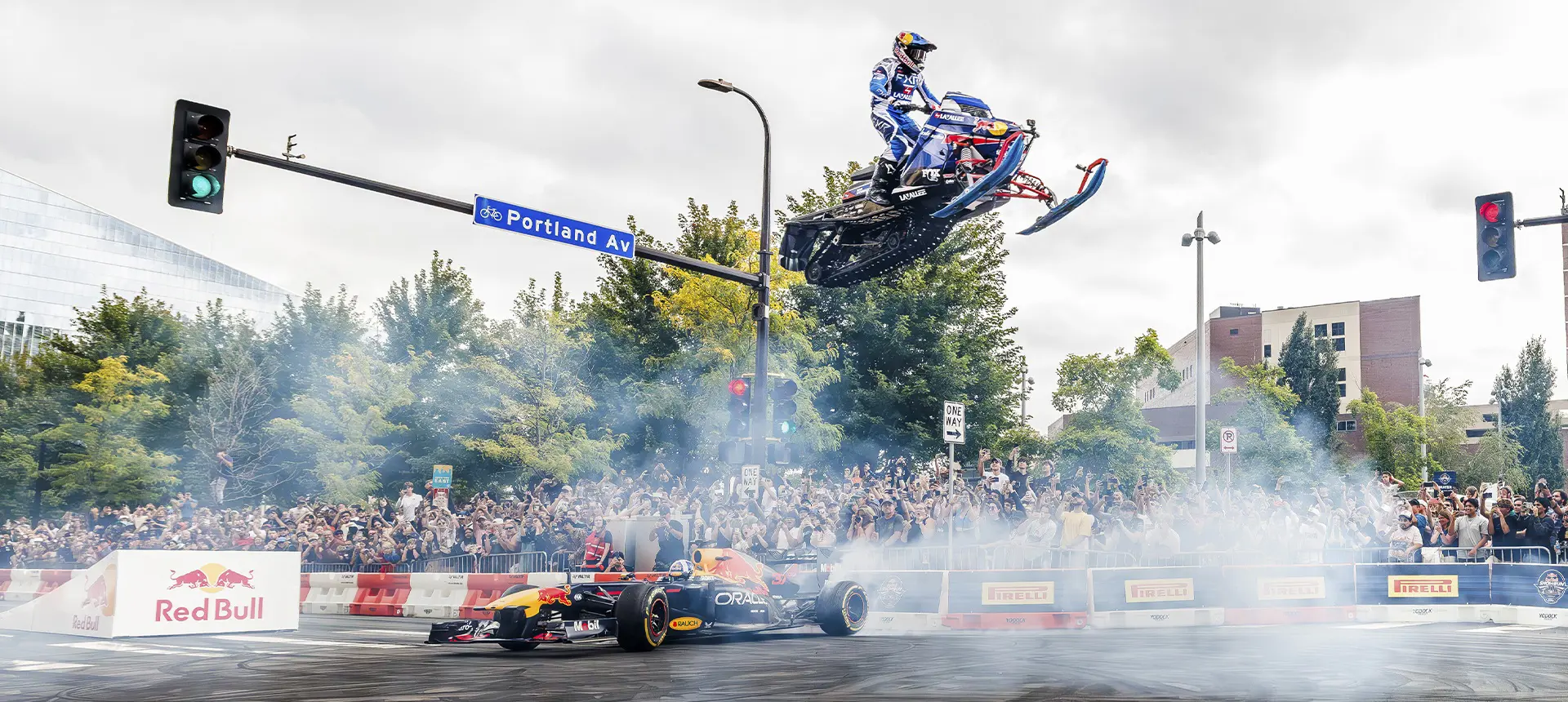 Levi LaValle jumping over a Red Bull Formula 1 car during a crowded city motorsports event.