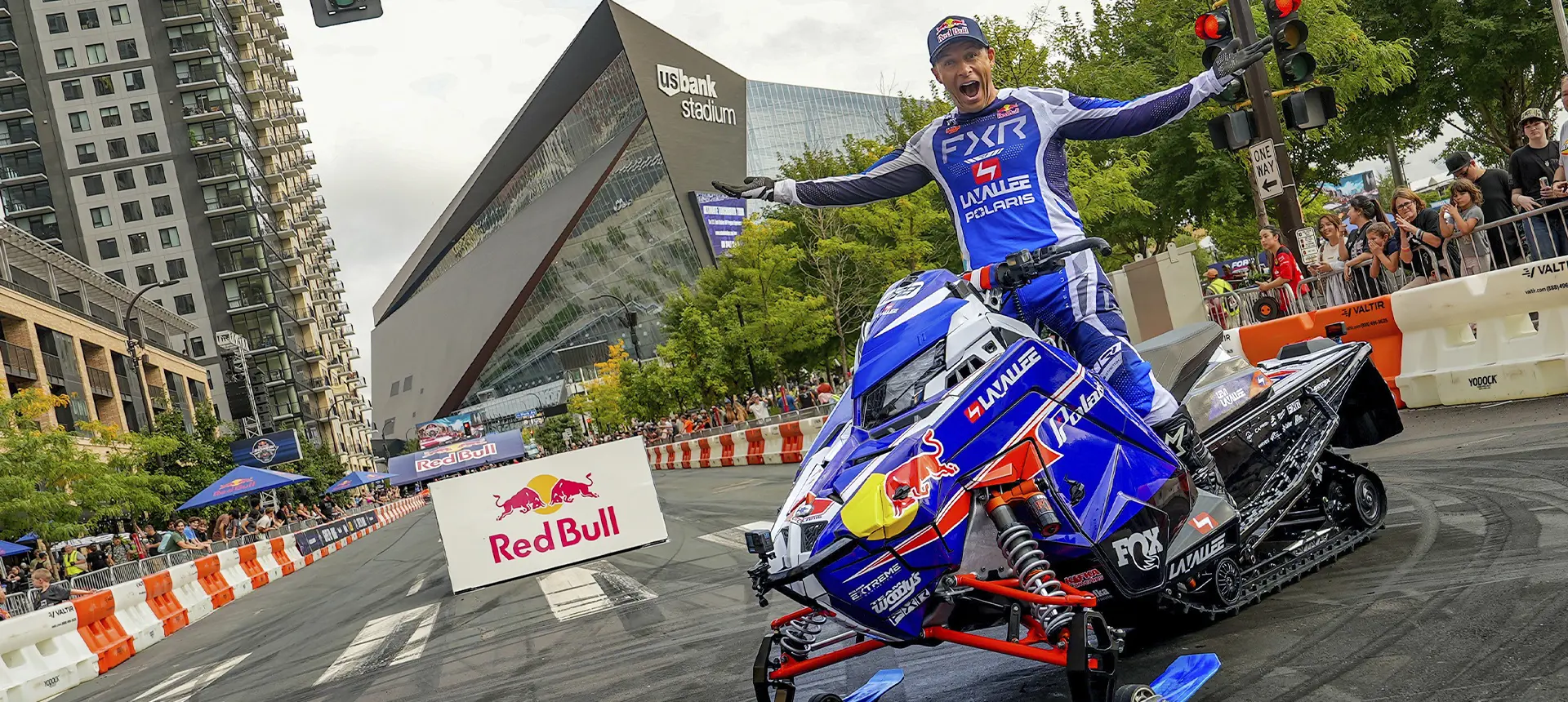 Levi LaValle standing on a custom race sled outside U.S. Bank Stadium during a city motorsports event.