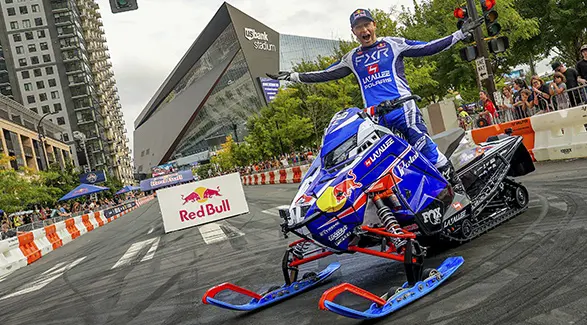Levi LaValle standing on a custom race sled outside U.S. Bank Stadium during a city motorsports event.