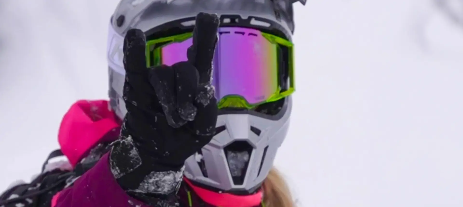 Close-up of Mikaela Grönlund in colorful winter gear and mirrored goggles making a hand gesture.