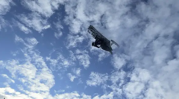 Ty Desrochers performing an aerial stunt beneath a blue sky filled with clouds.