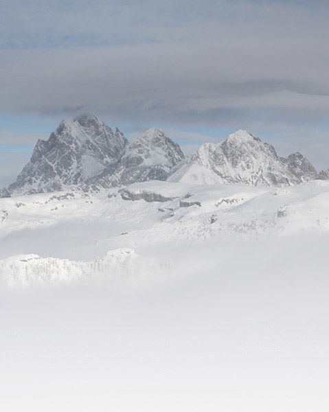 Panoramic view of rugged snow-covered mountain peaks rising above a misty alpine landscape.
