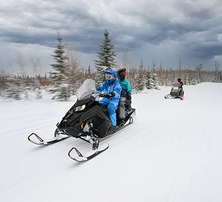 2 riders on a 2-up 2027 INDY Adventure snowmobile using the Lock & Ride Flex M2 passenger seat.
