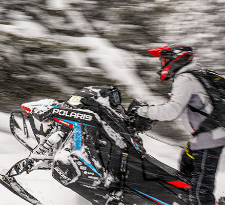 Rider showcasing the Patriot Boost engine on a 2027 Polaris RMK Factory Edition mountain snowmobile.