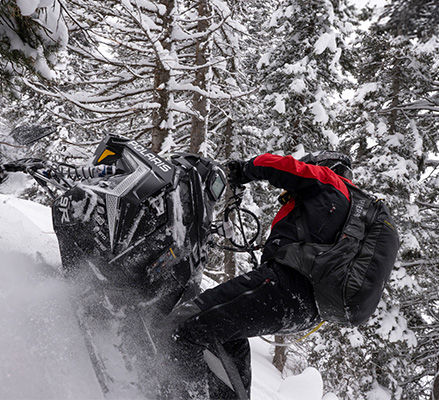 Rider showcasing the QuickDrive lightweight drive system on a 2027 Polaris RMK Factory Edition mountain snowmobile.