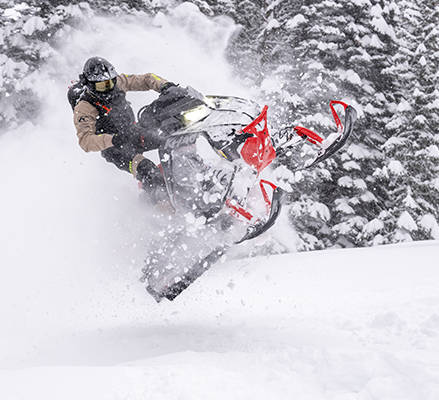 A rider showcasing the narrow build and tapered tunnel of a 2027 Polaris RMK Khaos mountain snowmobile.
