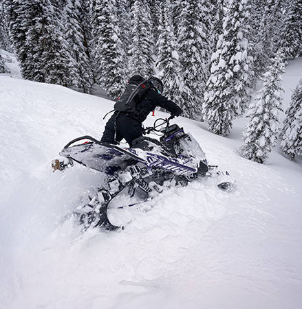 Rider showcasing the centralized cooling system featured in the 2027 Polaris RMK Khaos mountain snowmobile.