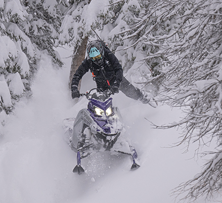 A rider showcasing the rigid chassis of a 2027 Polaris RMK Khaos mountain snowmobile.