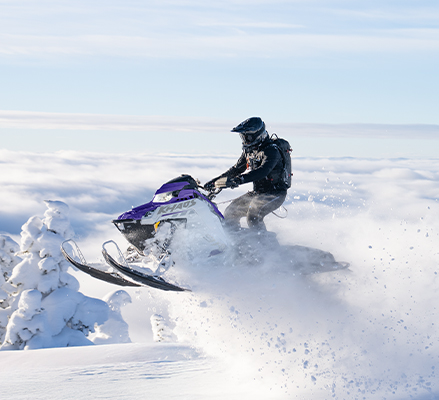 A rider showcasing the QuickDrive drive system of a 2027 Polaris RMK Khaos mountain snowmobile.