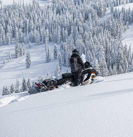 Rider on a 2027 Polaris RMK SP mountain snowmobile showcasing the full-length cooler and tapered tunnel.