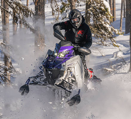 Rider on a 2027 Polaris Switchback Assault crossover snowmobile showcasing the front suspension options.