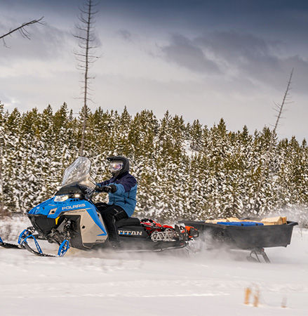Rider on a 2027 TITAN Nordic Pro widetrack snowmobile pulling a heavy sled with ease.