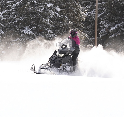 Rider showcasing the ProStar S4 4-stroke engine on the 2027 Polaris Voyageur Adventure sport-utility snowmobile.