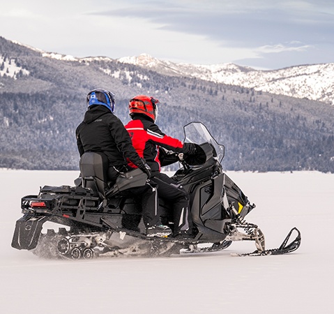 2 riders on a 2027 Polaris Voyageur Adventure sport-utility snowmobile showcasing the BackTrak15 rear suspension.