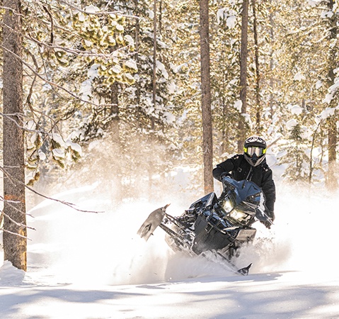 Rider cruising down a trail on a 2027 Polaris Snowmobile with the 850 Patriot engine.