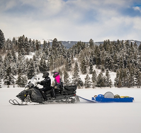 Side profile of a Polaris Snowmobile with the ProStar S4 4-stroke engine pulling a heavy sled with ease.