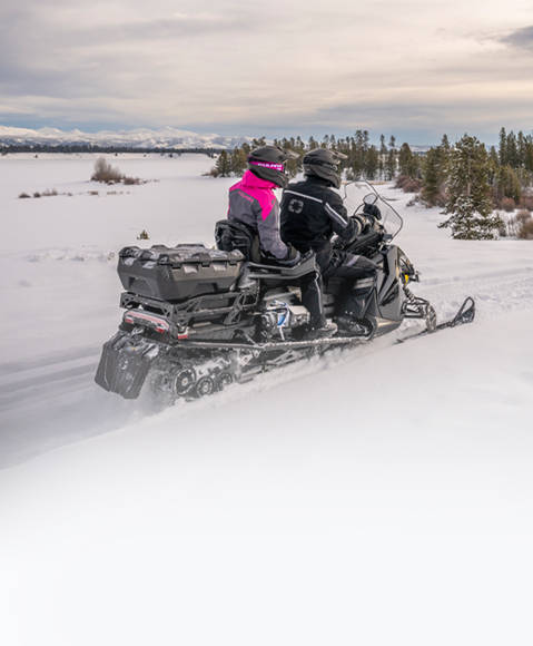 A rider pulling a sled with gear with a 2026 Polaris TITAN widetrack snowmobile.