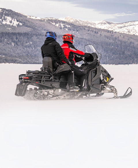 2 riders cruising on a 2027 Polaris Voyageur sport utility snowmobile.