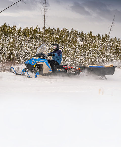 Rider pulling a heavy sled with a 2027 Polaris TITAN widetrack snowmobile.