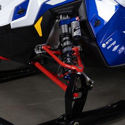 Close-up of the 2027 Polaris 600 INDY Cross Country snowmobile front suspension and red control arms.