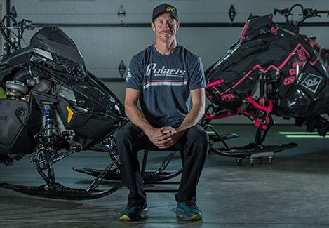 Chris Burandt sitting between two Polaris Snowmobile vehicles