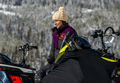 Polaris Ambassador, Mandy Fabel standing next to her Snowmobile vehicles