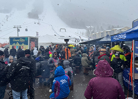 Crowds gathering near the Polaris booth during a snowy outdoor snowmobile Winter Tour event at a mountain resort.
