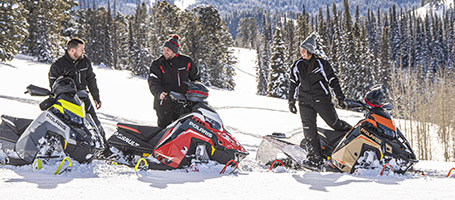 A group of Snowmobile riders chilling next to their Polaris vehicles